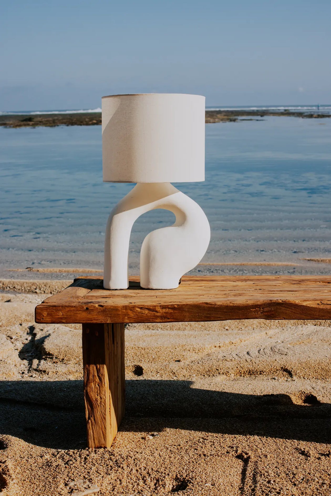 Reclaimed teak coffee table on the beach and ceramics table lamp